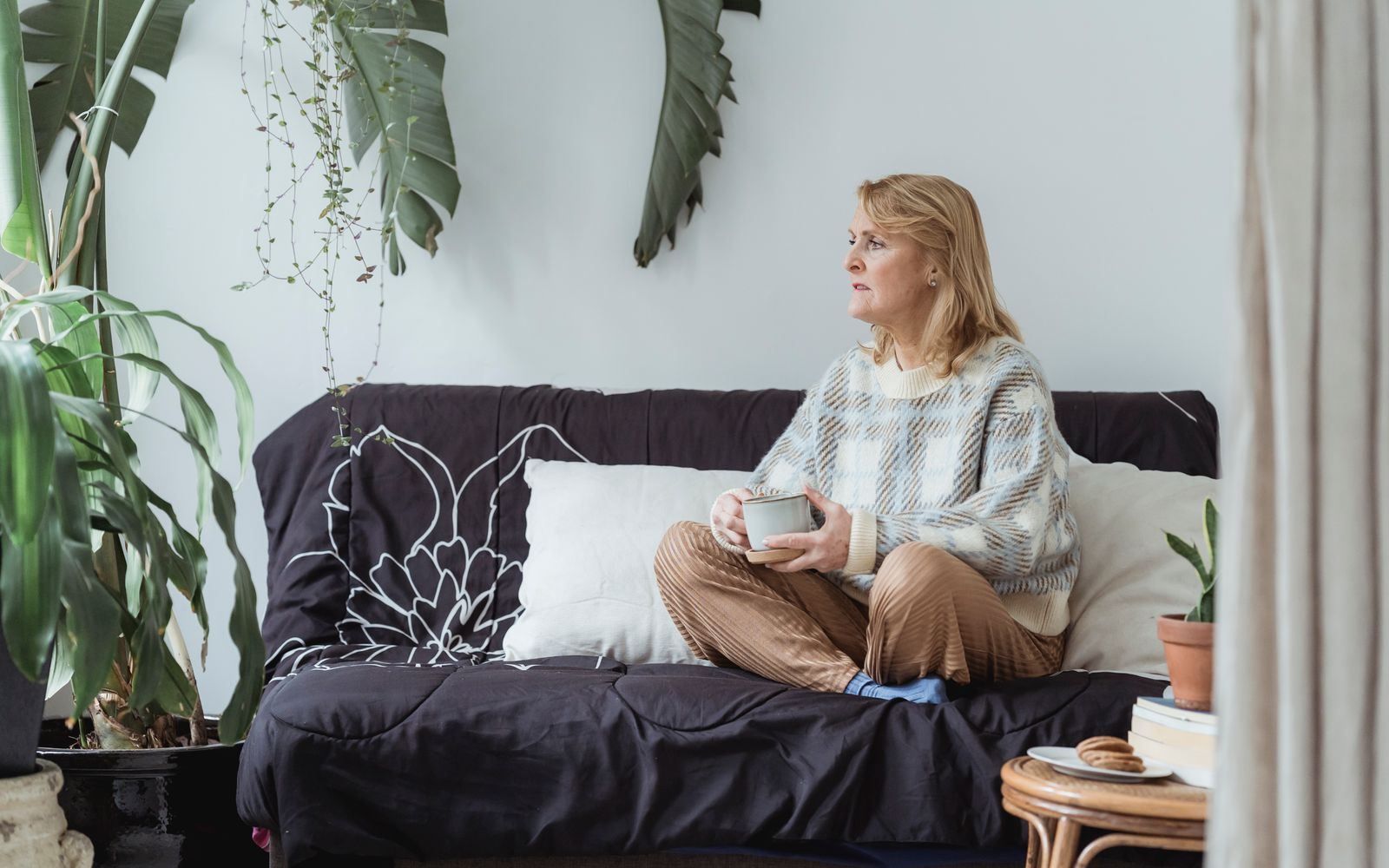 A thoughtful woman relaxing on a couch with a hot drink